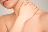 a close-up shot of a young naked woman who suffering from osteochondrosis, experiencing neck pain, holding her hand to her neck.