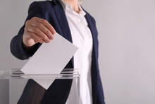 Woman Putting Her Vote Into Ballot Box On Light Grey Background, Closeup. Space For Text