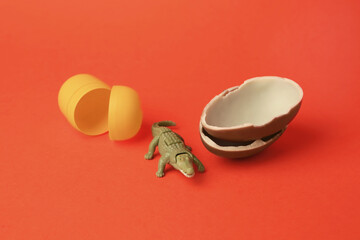 Sticker - Slynchev Bryag, Bulgaria - May 25, 2023: Halves of Kinder Surprise Egg, plastic capsule and toy crocodile on orange background