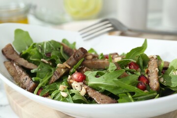 Delicious salad with beef tongue, arugula and seeds served on table, closeup