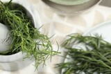 Fototapeta Lawenda - Plate and mortar with fresh tarragon leaves on table, above view