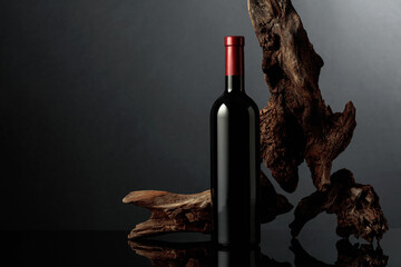 Poster - Bottle of red wine on a black reflective background.