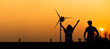 silhouette Hispanic brazillian couple standing together in front of wind turbine. Wind turbines for electric power and energy. Sustainable electricity production. Happy sucess hand up