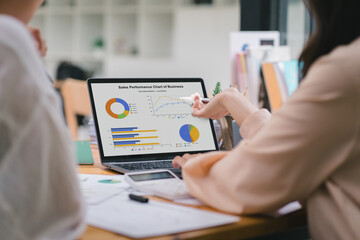 A businesswoman or accountant using laptop to analyze financial investments and business and marketing growth on a data graph. The concepts of accounting, economics, and commercial analysis.