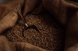 From above of metal scoop in burlap bag filled with aromatic roasted coffee grains