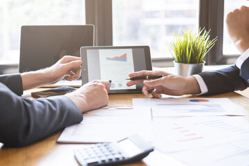 Business meeting, two caucasian, asian group man use tablet brainstorm analyzing on graph data of cost plan or document, paperwork and discussing in board room on table. People working conference room