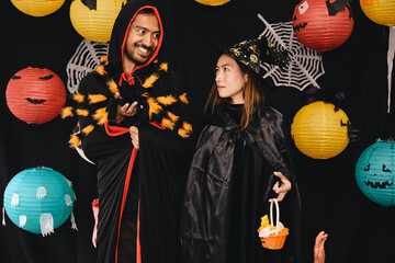 Asian young wizard Halloween man portrait and black spider on chest standing with witch Halloween woman portrait