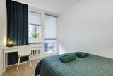 Fototapeta  - Jasna sypialnia z zielonym łózkiem i białym biurkiem do pracy
