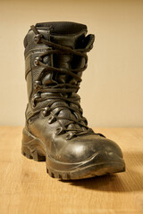 Second hand black leather army boots on the floor.