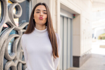 Wall Mural - pretty young adult woman pressing lips together with a cute, fun, happy, lovely expression, sending a kiss