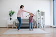 © sofiko14 - Active female parent and preteen child listening to uplifting melody while spinning on warm floor in modern apartment. True music lovers wiggling with popular rock and roll music in home interior.