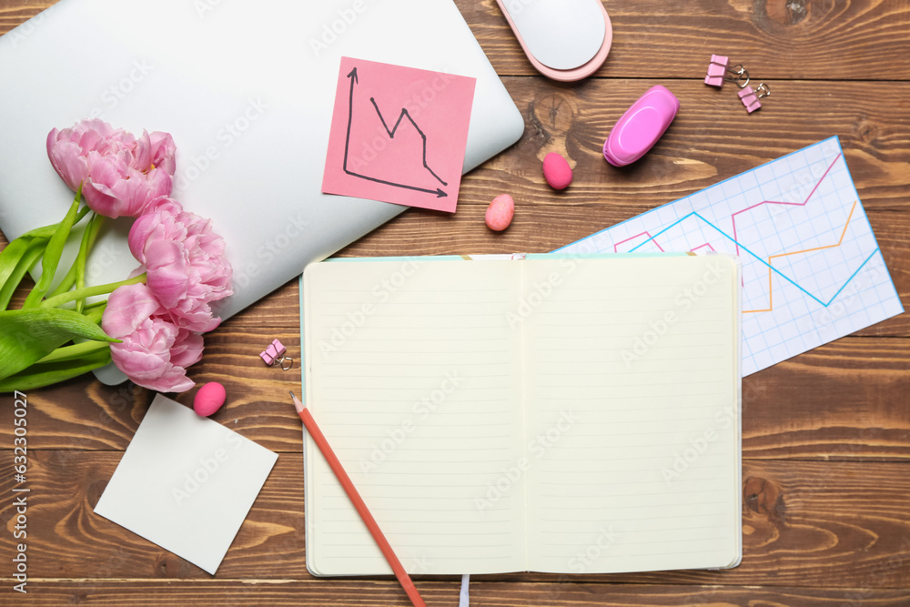 Blank notebook with office stationery, laptop, tulips and Easter eggs on wooden background
