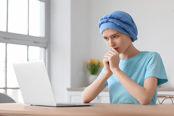 Sticker - Teenage girl after chemotherapy using laptop at table in kitchen