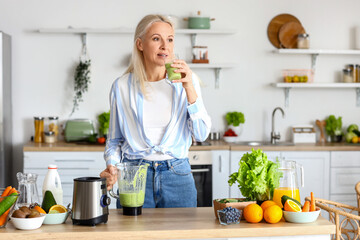 Canvas Print - Mature woman with glass of healthy smoothie in kitchen