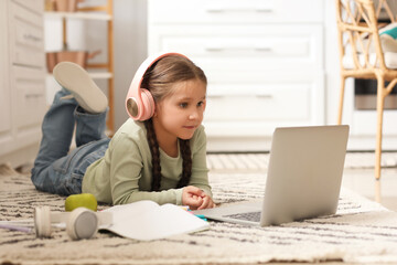 Poster - Little girl in headphones with laptop studying computer sciences online at home