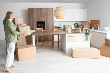 Wall Mural - Mature couple with cardboard boxes in kitchen on moving day