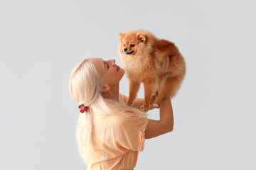 Poster - Mature woman with Pomeranian dog on light background