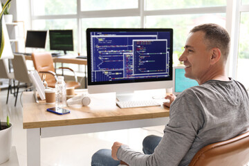 Poster - Mature male programmer sitting in light office at his workplace