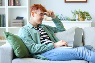 Canvas Print - Young redhead man using laptop on sofa at home