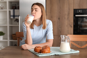 Wall Mural - Young woman drinking milk in kitchen