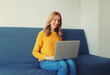 © rohappy - Modern young woman working with laptop sitting on the couch in the room at home