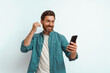 © Daria - Smiling man showing happy gesture while looking to his mobile phone on white background