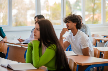 Wall Mural - In the classroom group of college students listening to a lecturer and writing in notebooks.