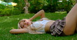 Pretty Asian woman wearing miniskirt lies on the grass in a public park