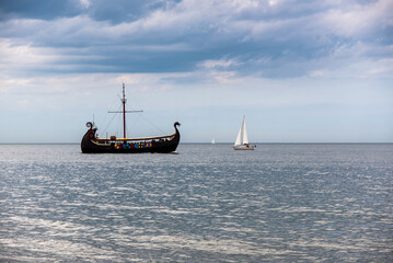 A ship stylized as a Viking boat rides tourists on the Baltic Sea, next to it are two sailing boats