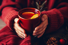 Hands holding a mug of hot mulled wine close-up