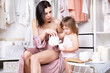 © Looksa - Young beautiful slender mother playing in morning in bright dressing room with her little daughter.