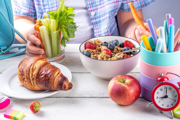 Healthy nutritious  morning breakfast for school kids, with fresh fruits, vegetables, croissant, muesli, milk and sandwich. Child girl having breakfast before school and work, copy space