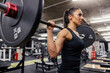 © dusanpetkovic1 - A strong woman is doing exercises with barbell in a gym for her biceps and shoulders.