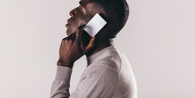 Making The Call To Premium Electronic Banking: Young Black Man Holds A Credit Card Over His Ear In A Studio
