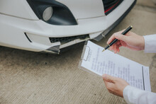 An Insurance Agent Inspects The Damaged Vehicle And Submits A Post-accident Claim Form. Traffic Accident And Insurance Concept