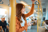 Fototapeta  - Happy young Asian woman passenger smile and using smart mobile phone in subway train station, lifestyle, transportation.