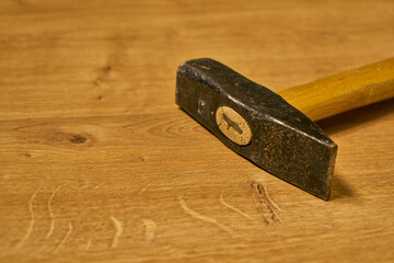 Old style, classic carpenter hammer with a wooden handle on a wooden table.