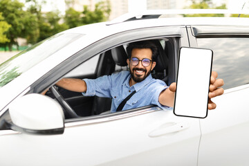 Smiling young eastern man sitting in auto, showing phone