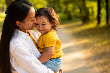 Wall Mural - Portrait Of Korean Mother Hugging And Holding Baby Daughter Outdoors