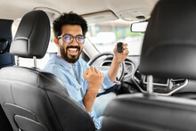 Cheerful arab man holding key from auto, buying new car