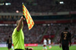 Raised flag of the sideline referee during football match.