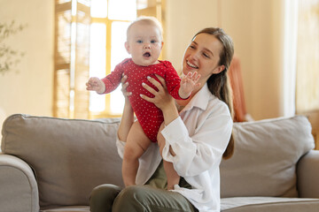 Wall Mural - Young happy mother holding to her cute baby child at home