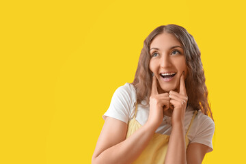 Sticker - Happy young woman touching her cheeks on yellow background