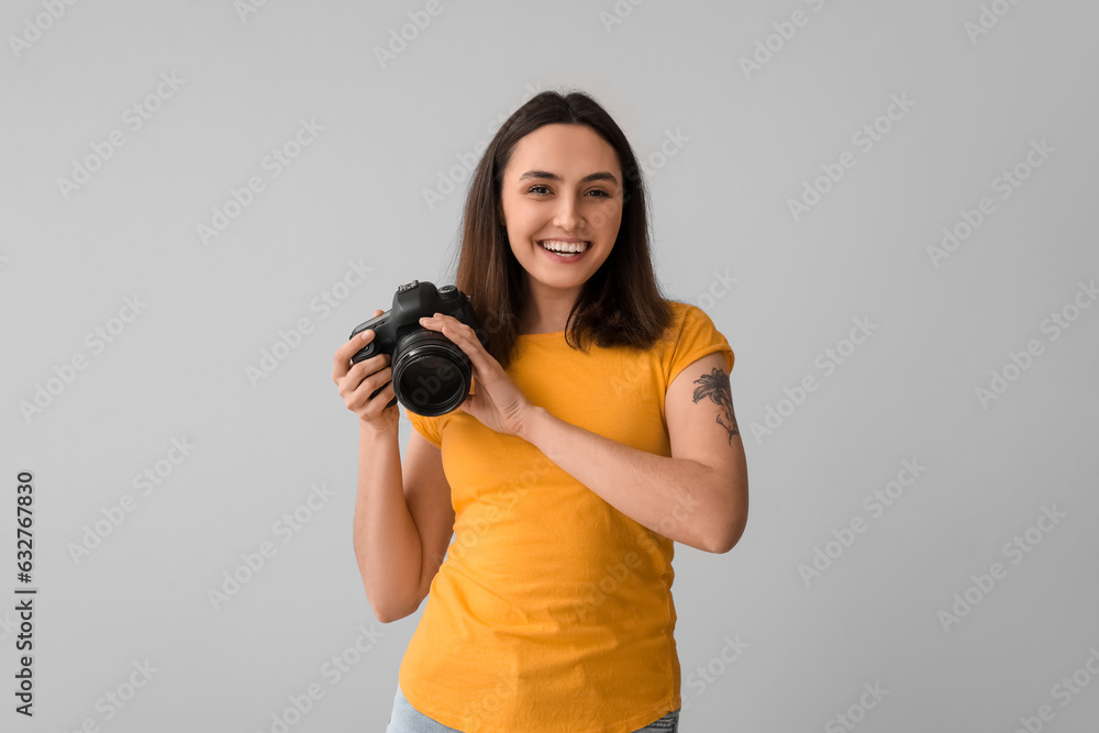 Female photographer with professional camera on grey background