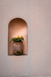 Photo of a clay planter with flowers in an alcove on a building wall