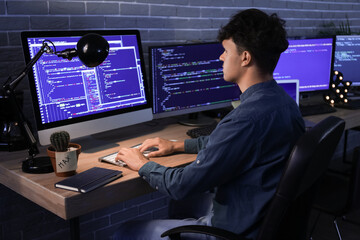 Male programmer working with computer in office at night