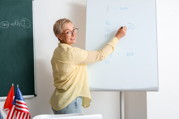 Poster - Female teacher writing English grammar on flipboard in classroom