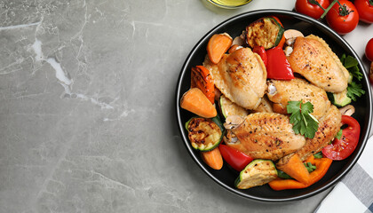 Delicious cooked chicken and vegetables on grey marble table, flat lay with space for text. Healthy meals from air fryer