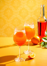 Aperol Spritz Cocktail With Ice, A Misted Refreshing Drink, On An Orange Background, Sunlight, Shadows, A Summer Drink In A Wine Glass
