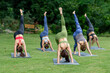 © Sirirat Makprasert - Yoga group people training and warrior pose attending yoga outside at park in sunset; group of asian young women yoga exercising training in serene ocean; select focus.